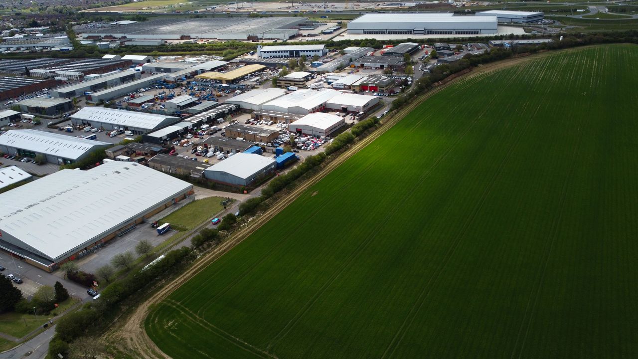 Aerial view showcasing the industrial park and lush green fields in Luton, England.